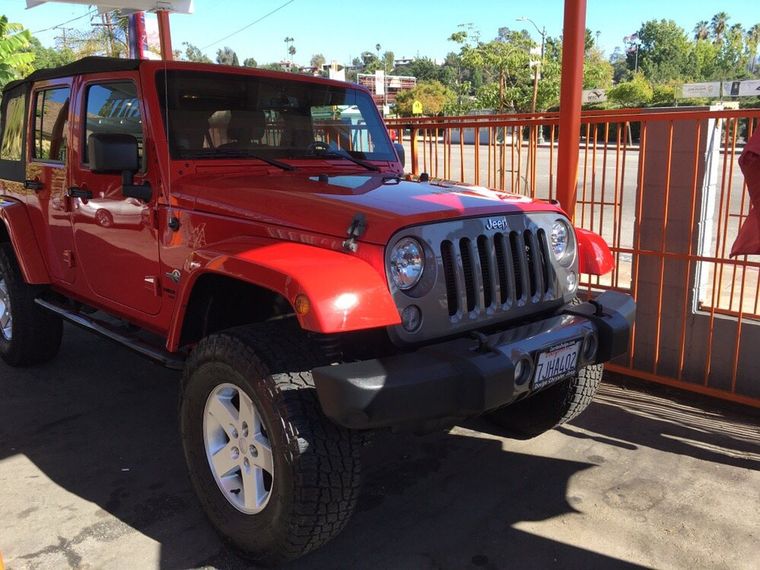 A red Jeep Wrangler parked beside the orange railing at the edge of the lot.